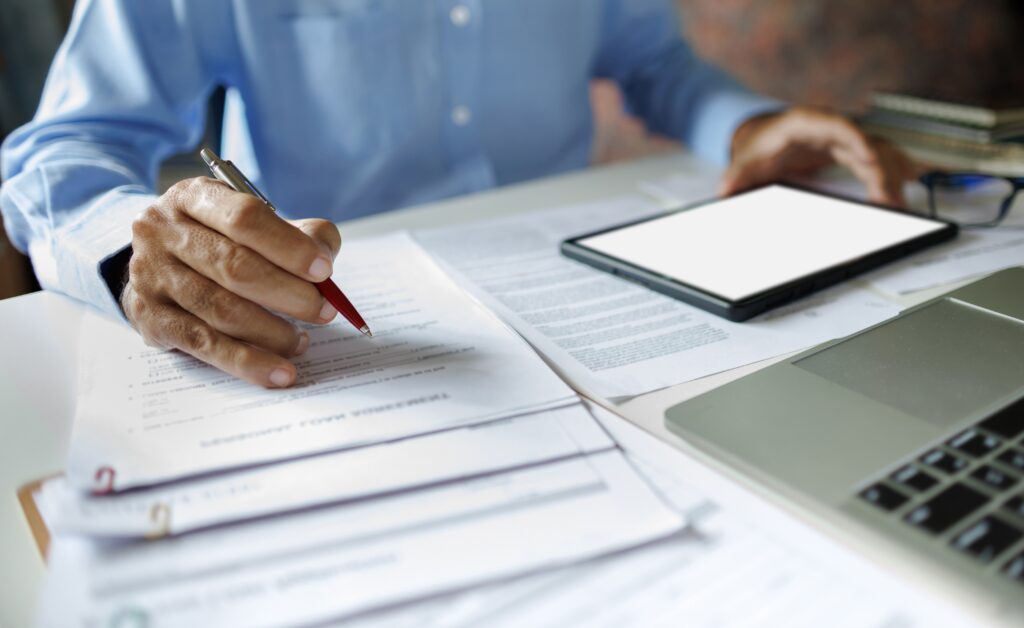 man looking over paperwork, holding a pen