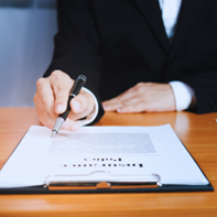 Person pointing a pen at legal papers on a clipboard that is sitting on a table.